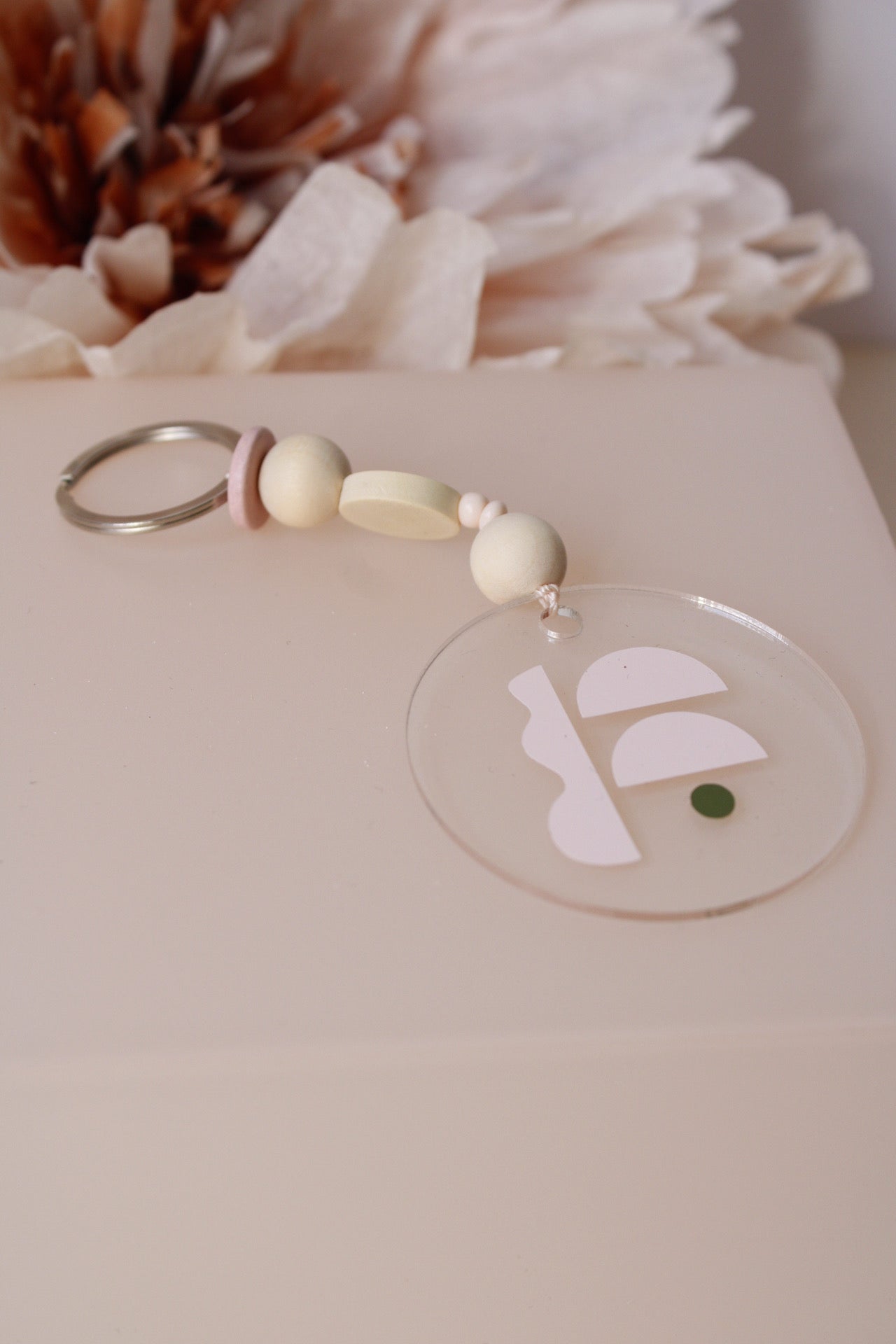 Acrylschluesslanhaenger mit geometrischer Form und Perlen, auf Kästchen liegend fotografiert