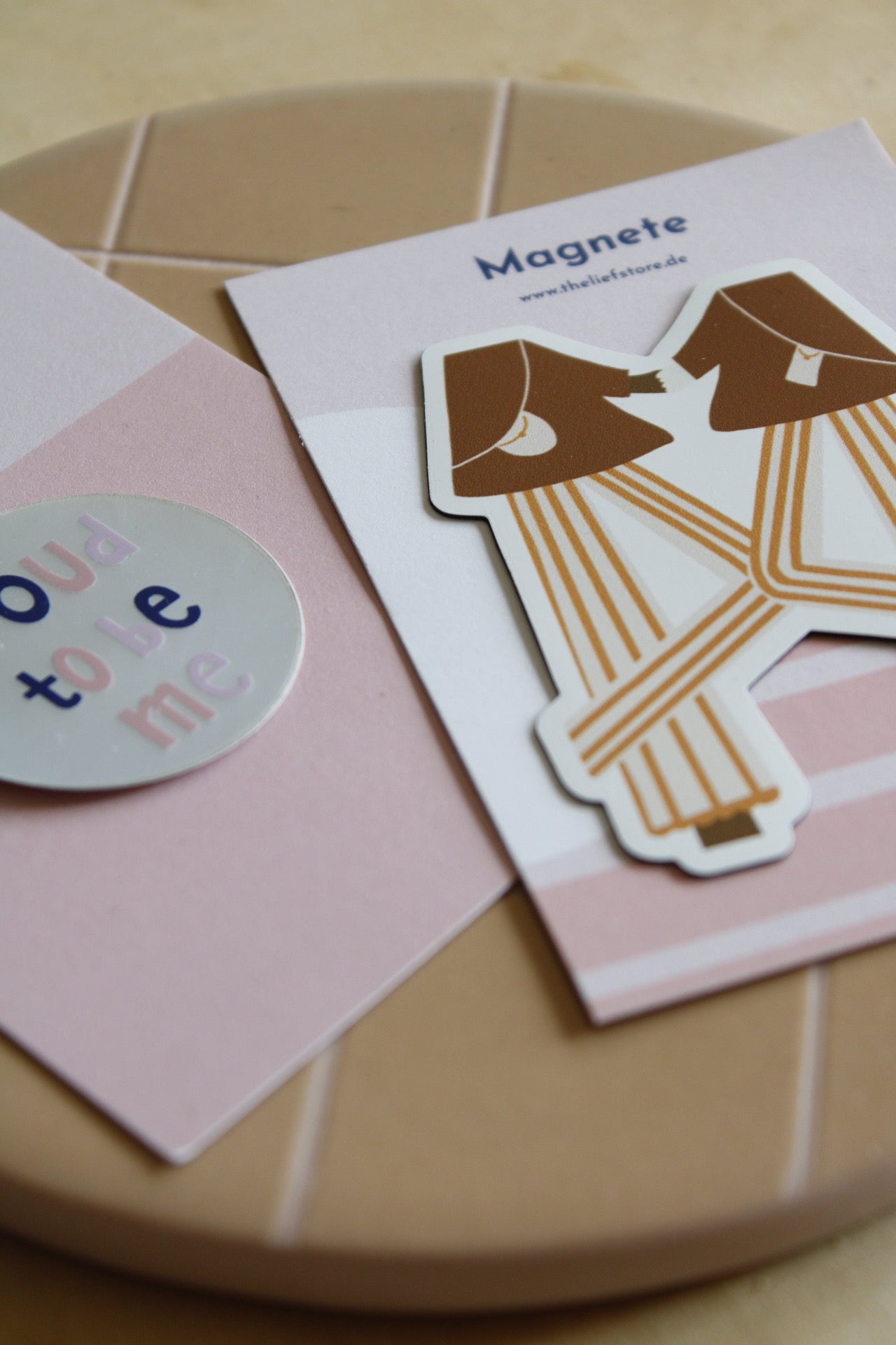 Runder Sticker und Magnet auf heller, gestreifter Keramikplatte.