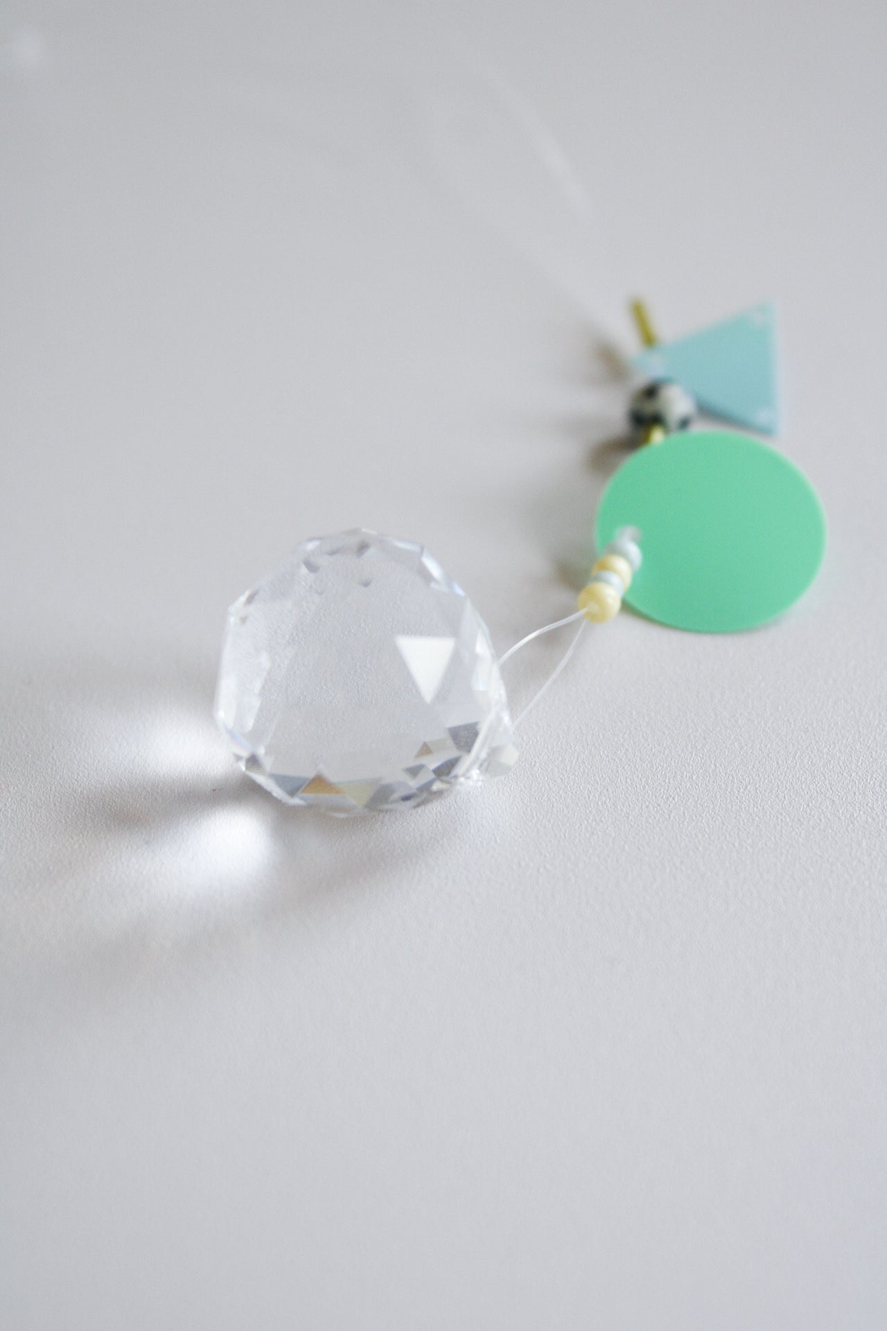 ein kleiner Suncatcher mit blauen Perlen und Dalmatinerperle, liegend, fokussiert