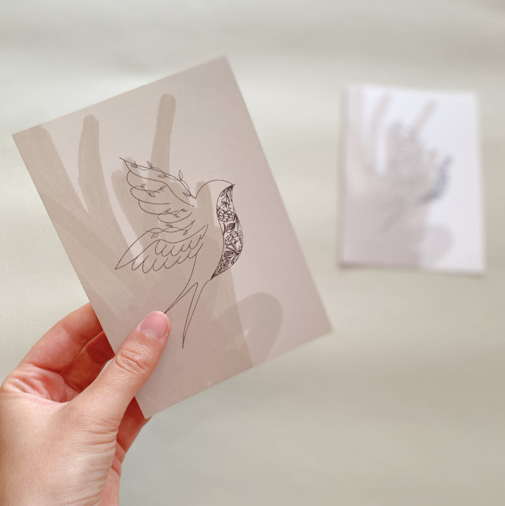 Trauerkarte ‚Schwalbe mit Blumen‘ – Elegante Beileidskarte mit floralen Motiven, Karte wird von Hand gehalten