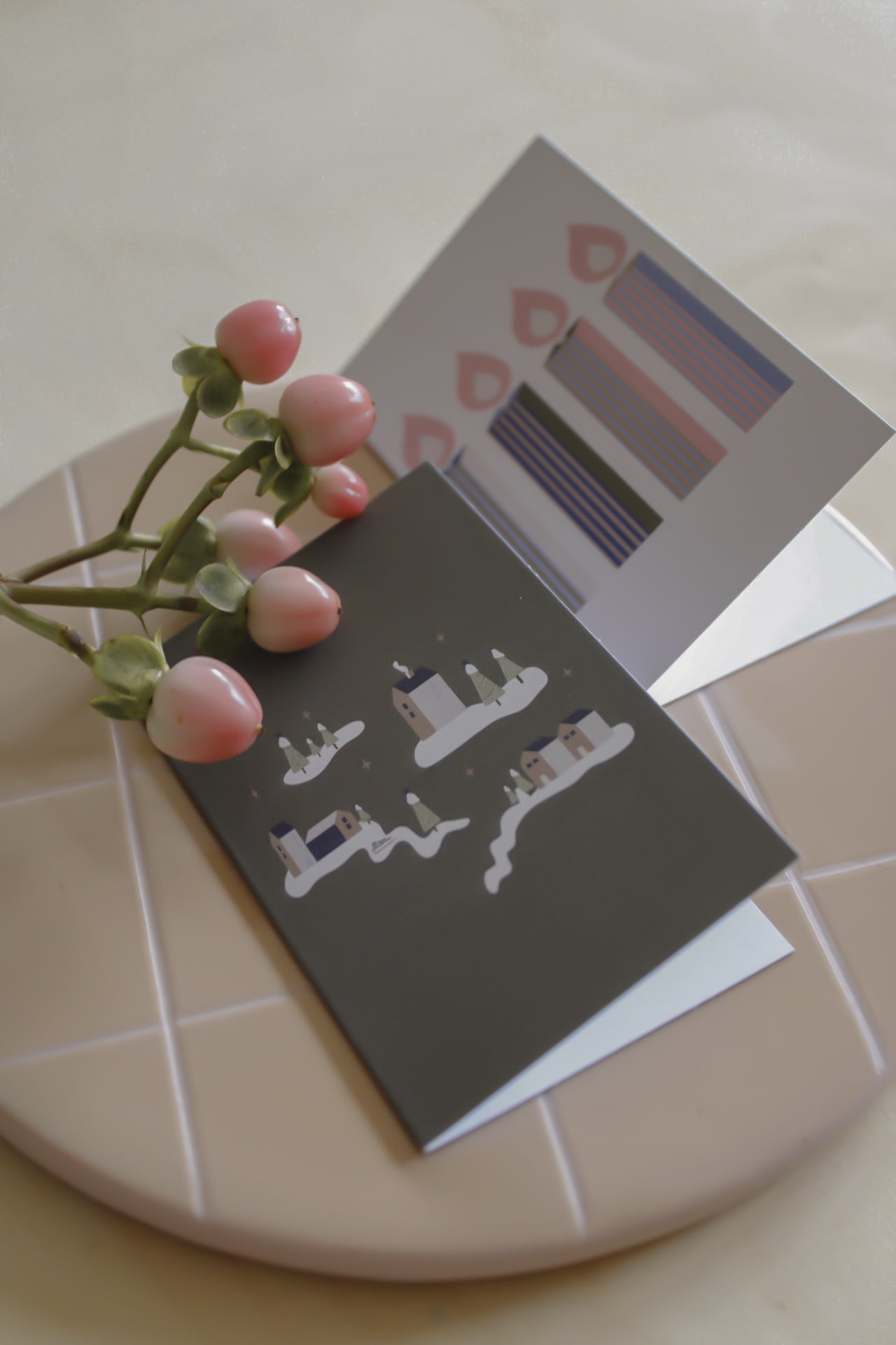 Weihnachtliche Mini Klappkarten als Geschenkanhänger mit zwei Motiven im4er Set. Fotografiert auf einem kariertem Keramikbrett mit Blumendekoration.