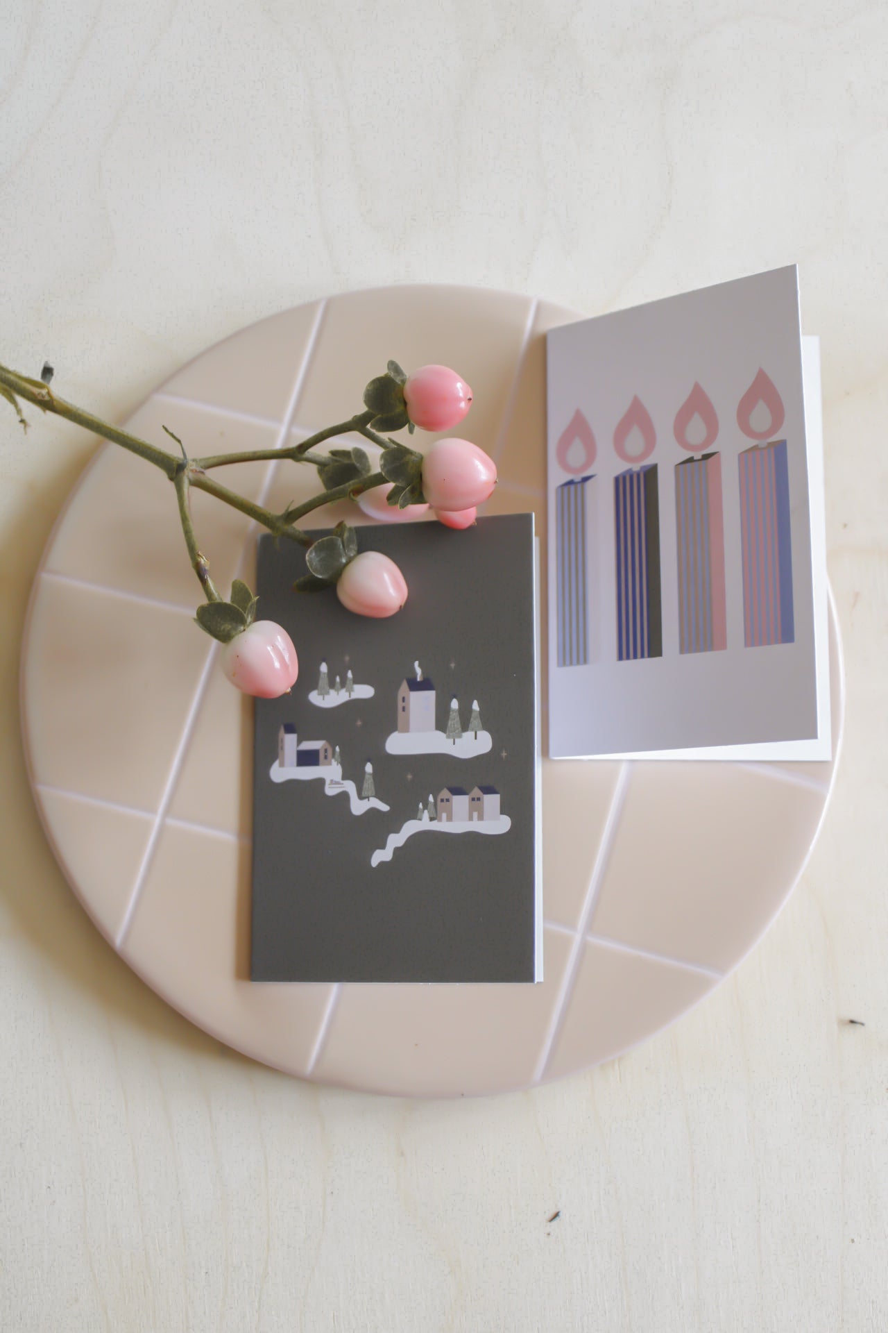 Zwei  Mini Klappkarten mit weihnachtlichen Motiven. Motiv links: Weihnachtliches Dorf mit Häusern,Bäumen und Schnee auf dunkelgrünem Hintergrund. 
Rechtes Motiv: 4 gestreifte Stabkerzen in bunten Farben auf rosa Hintergrund. 