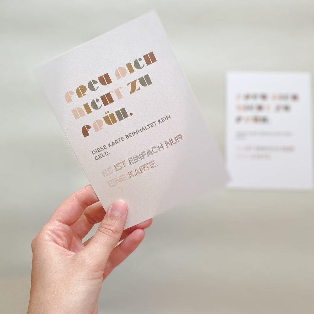 Postkarte ‚Freu dich nicht zu früh‘ – Humorvolle Typografiekarte, Vorderseite zu sehen, wird von Hand gehalten