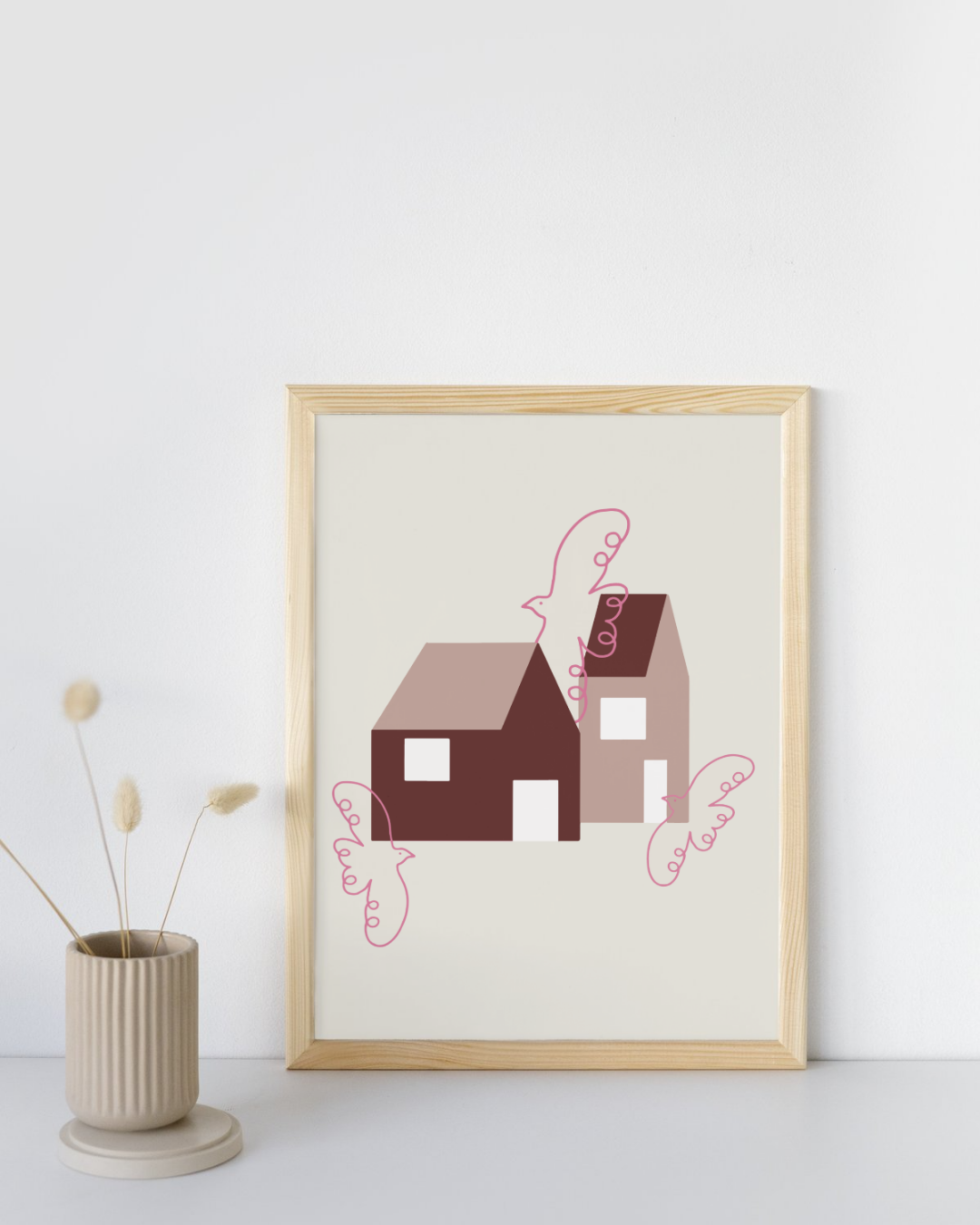 Poster auf DIN A4 mit zwei abstrakten Häusern und pinken Vögeln auf beigem Hintergrund. Das Poster ist in einem hellen Bilderrahmen eingerahmt und steht neben einer Vase.