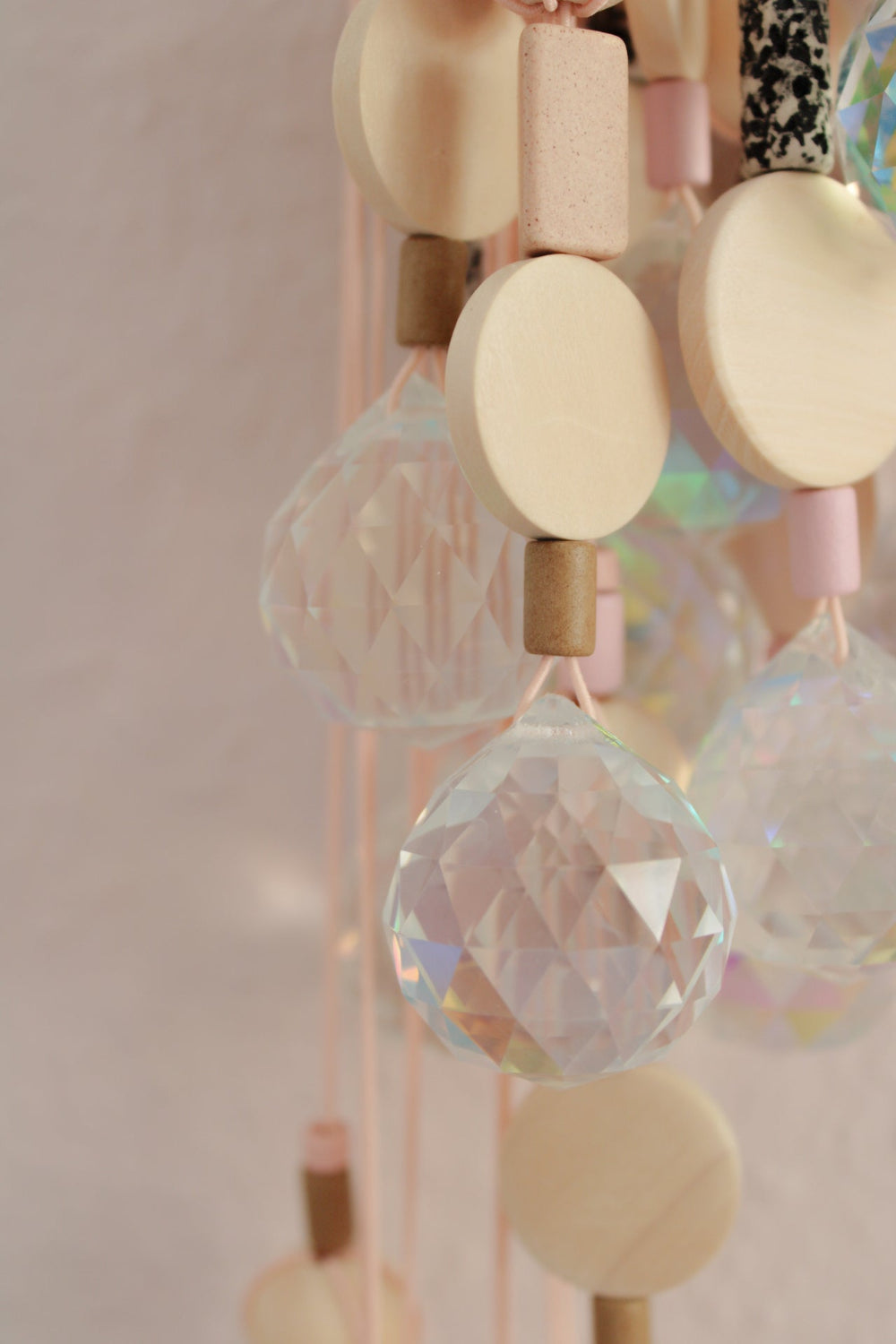 Detailaufnahme des Suncatchers ‚Schwarz‘ mit Holzperlen, Keramikperlen und rosa Band, mehere Suncatcher hängend zu sehen