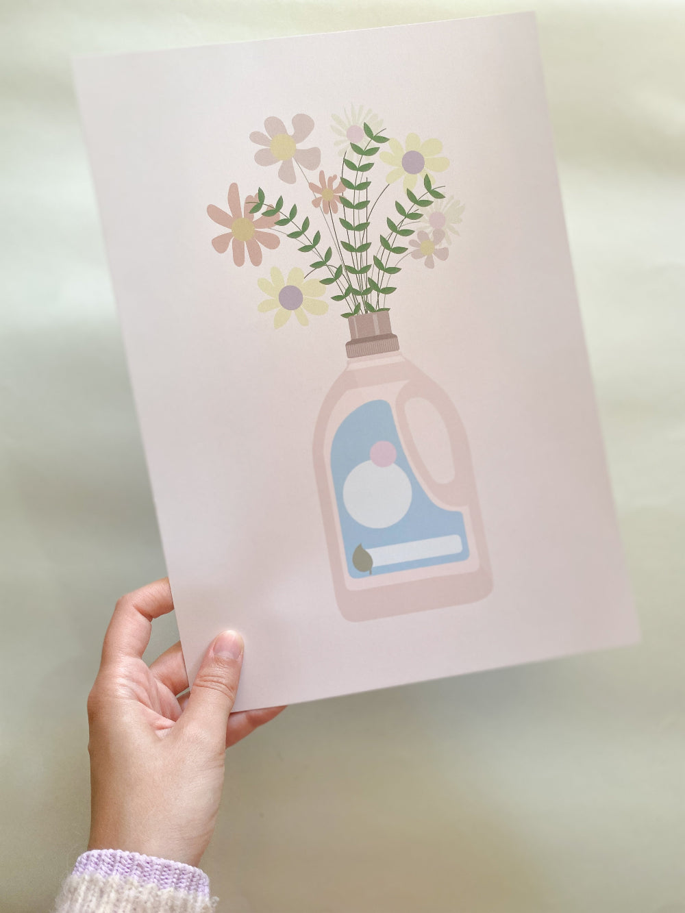 Handgezeichnetes ‚Waschmittel Blumen‘-Poster mit Waschmittelverpackung als Blumenvase für kreative Wanddekoration, Hand hält Poster